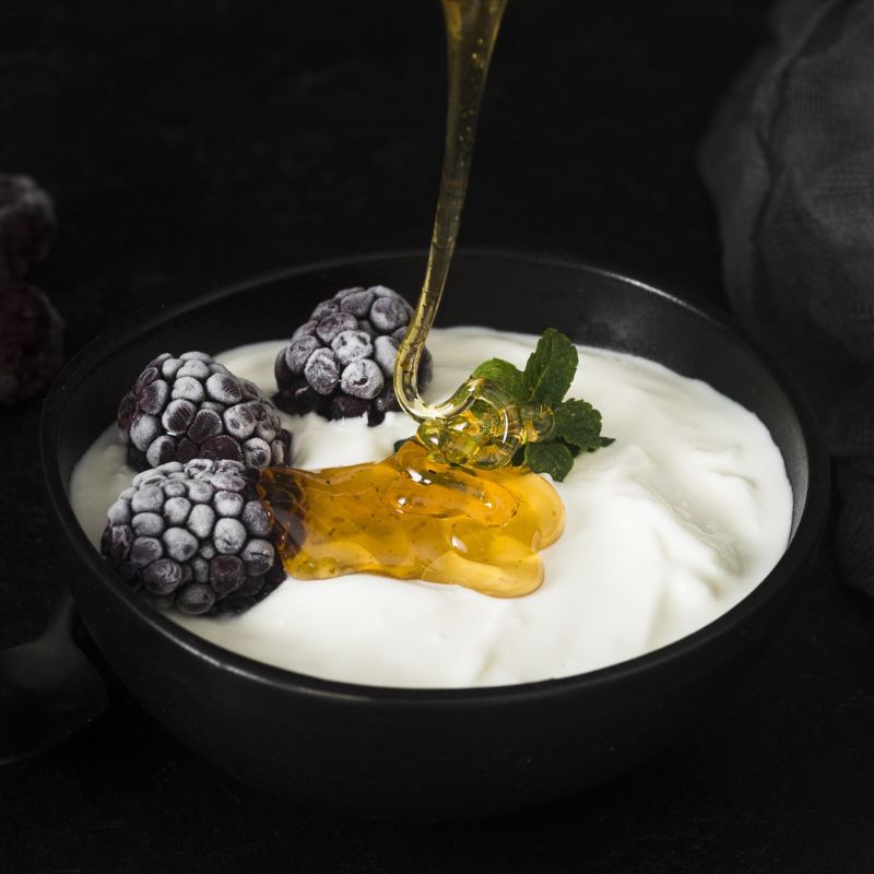 Jogurt z jeżynami w miseczce, polewany syropem Fabbri Mixybar Nocciola.