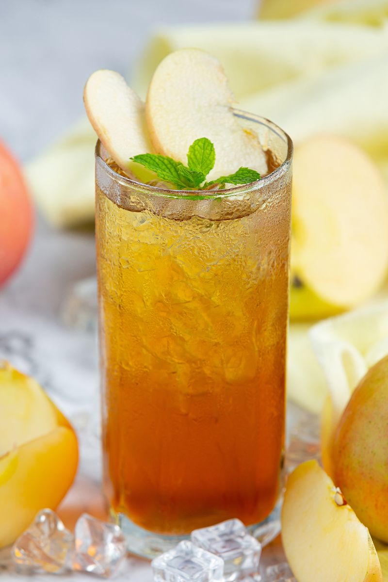 Lemon Verbena & Pear Cooler - napój na lato w wysokiej szklance. Prezentacja zkawałkami gruszki, miętą i kruszonym lodem.