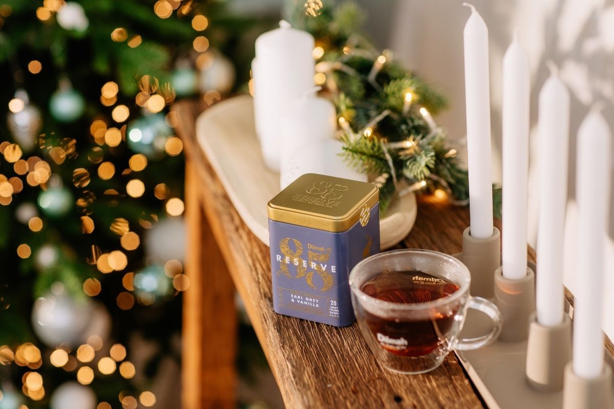 Puszka Herbaty Dilmah Earl Grey & Vanilla oraz filiżanka z naparem tuż przy choince.