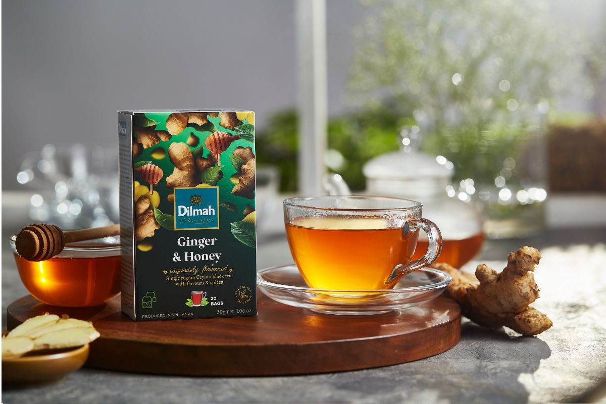 Herbata Dilmah Ginger & Honey w towarzystwie imbiru na stole w kuchni.