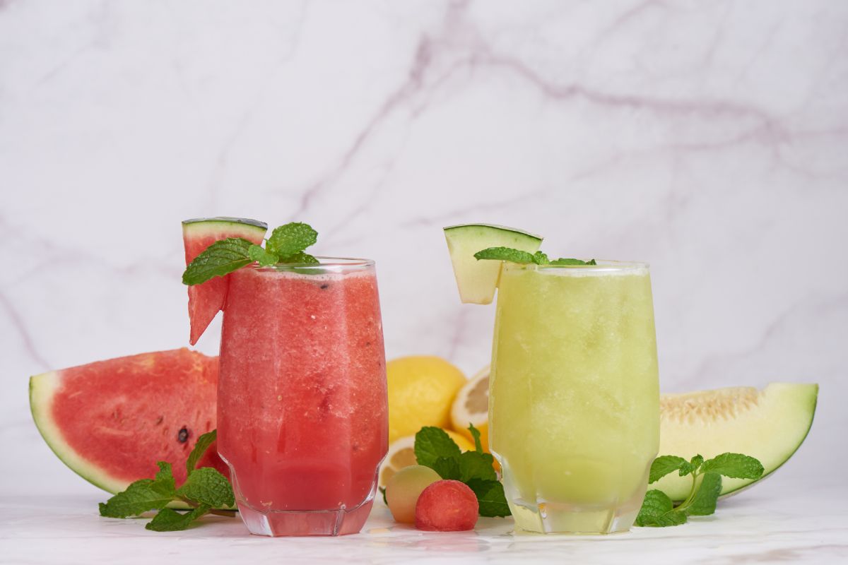 Dwie szklanki z lemoniadą arbuzową i lemoniadą melonową z kruszonym lodem i miętą.