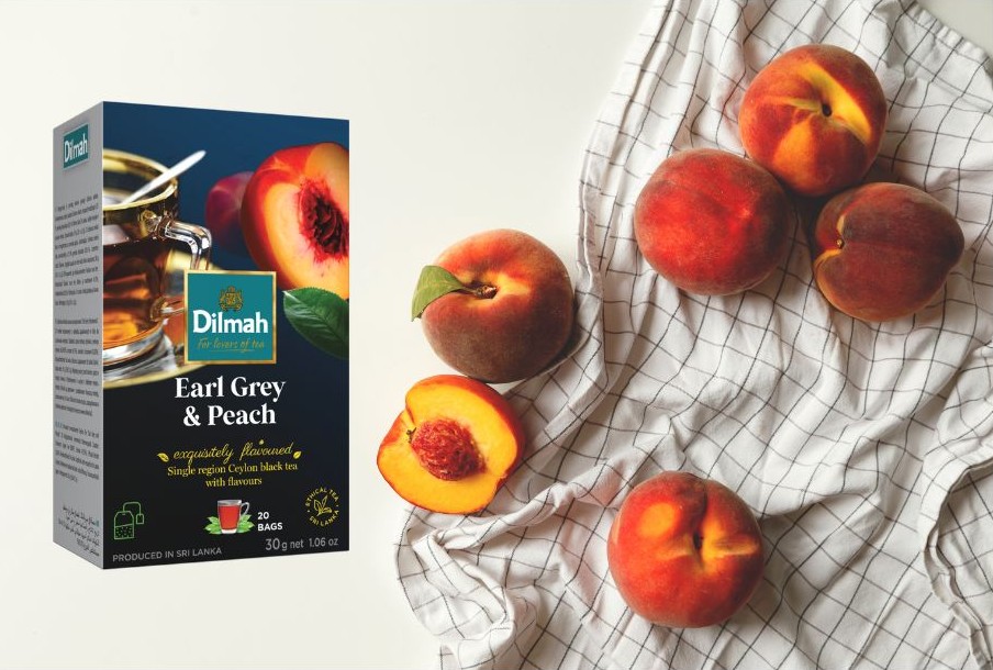 Herbata Dilmah Earl Grey & Peach. Obok soczyste brzoskwinie na kuchennym obrusie.
