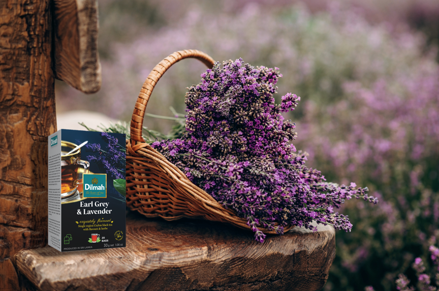 Herbata Earl Grey & Lavender obok koszyka z kwiatami lawendy. W tle lawendowe pole.
