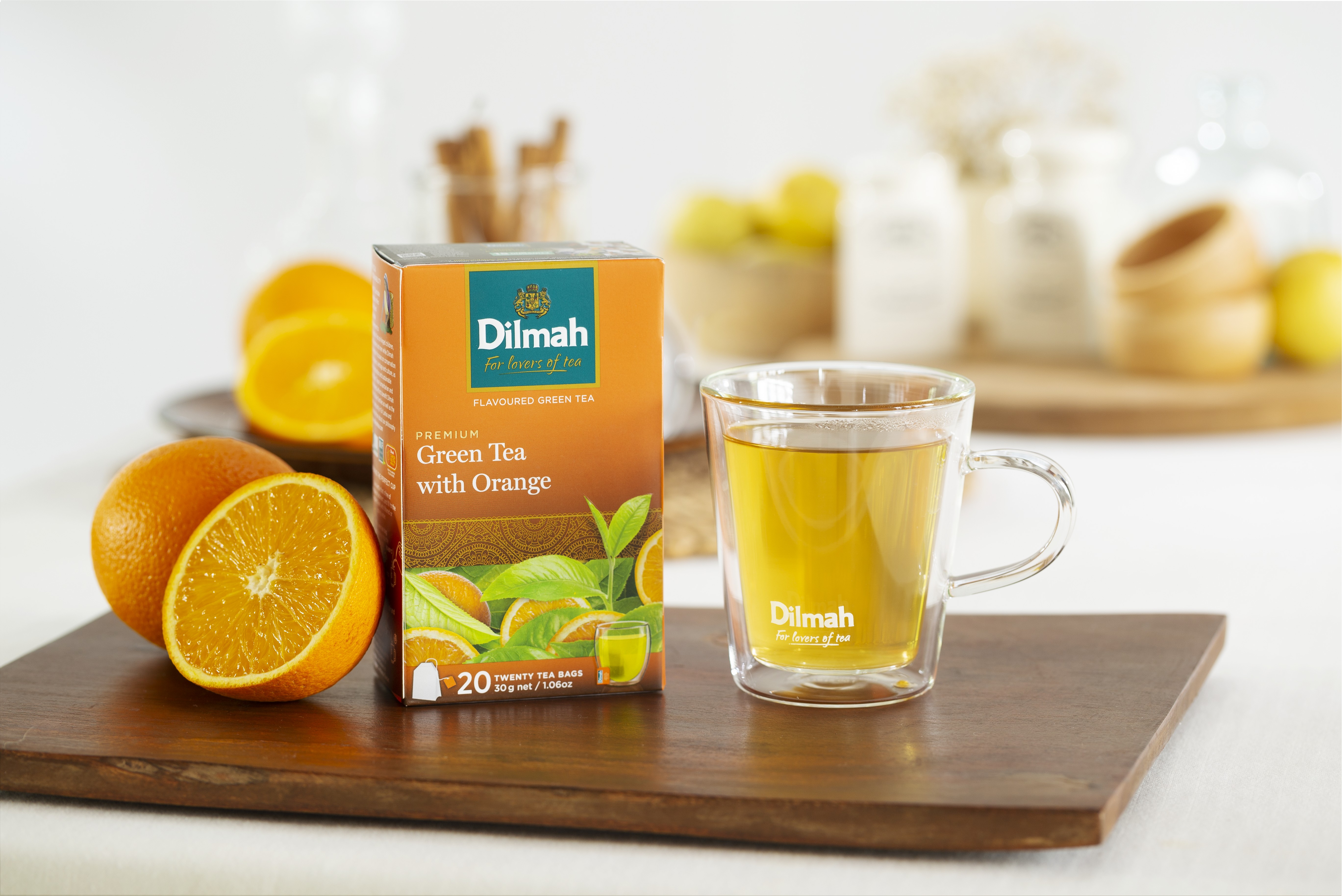 Dilmah Green Tea with Orange – herbata zielona z nutą cytrusów, opakowanie wśród owoców i szklanka gorącego naparu. Idealna propozycja na Wielkanoc.