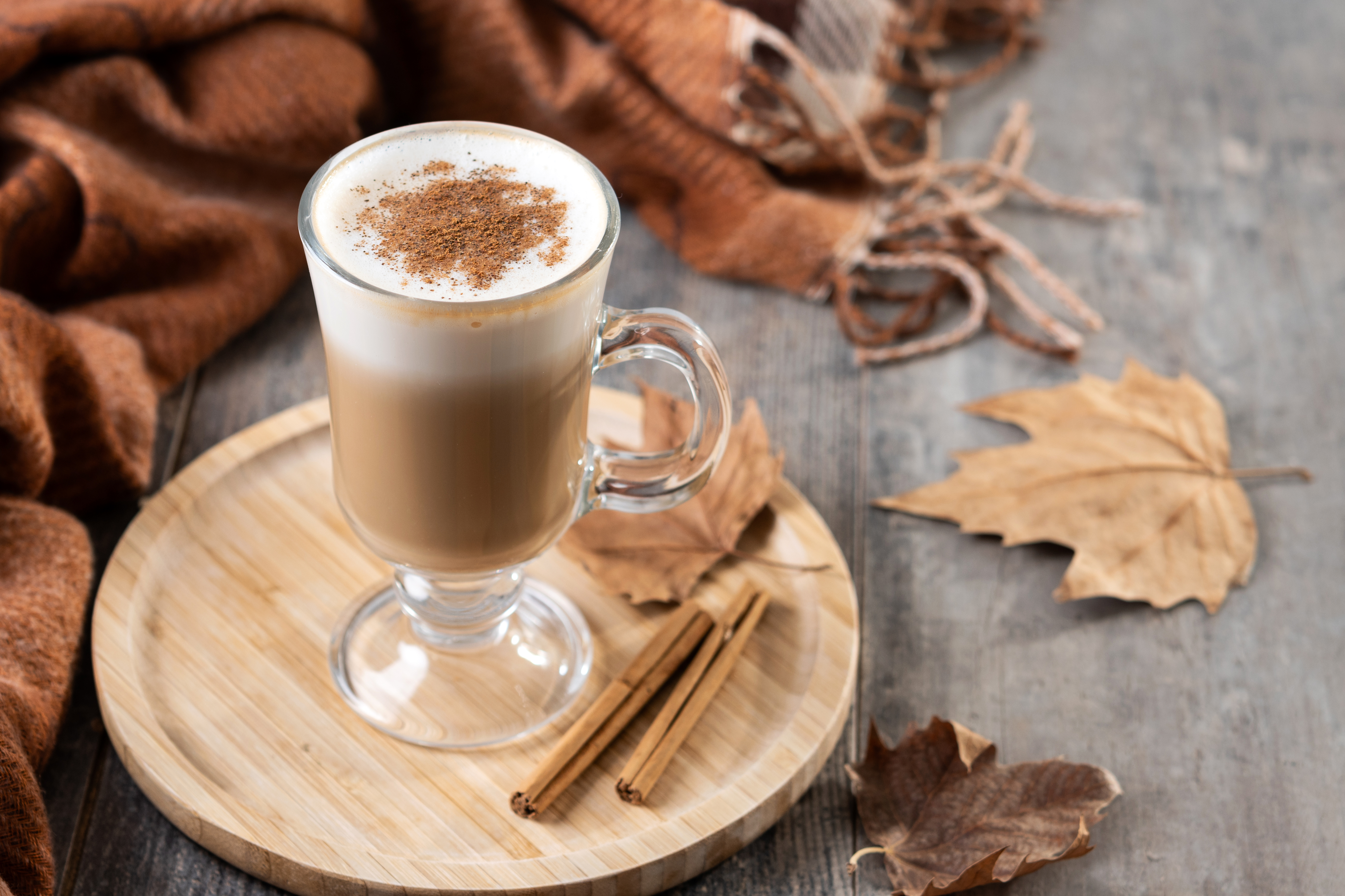 Kawa latte z cynamonem wśród jesiennych liści.