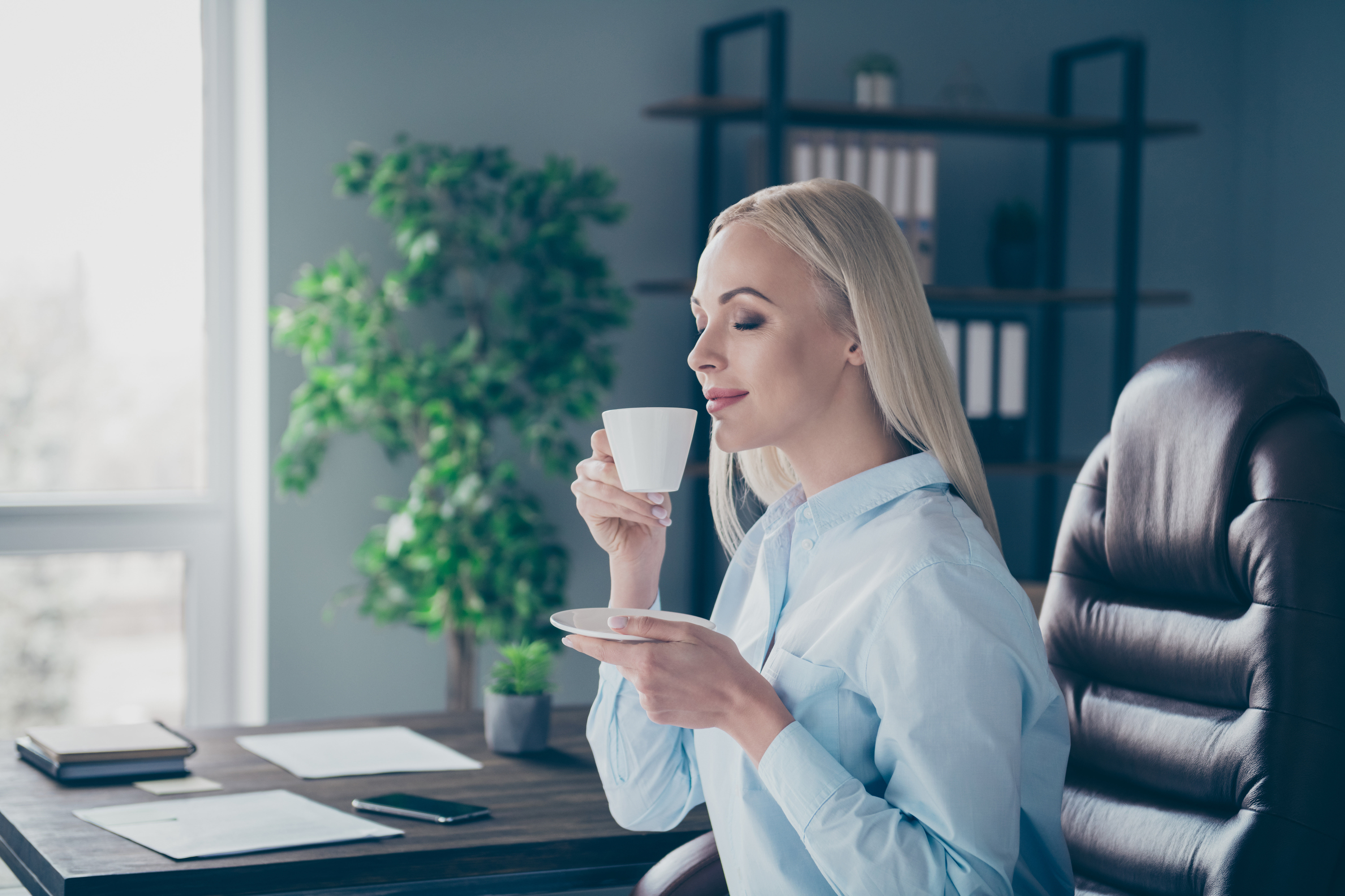 Kobieta delektująca się doskonałą kawą Saquella Gran Cru Espresso Ricco przy biurku w pracy.