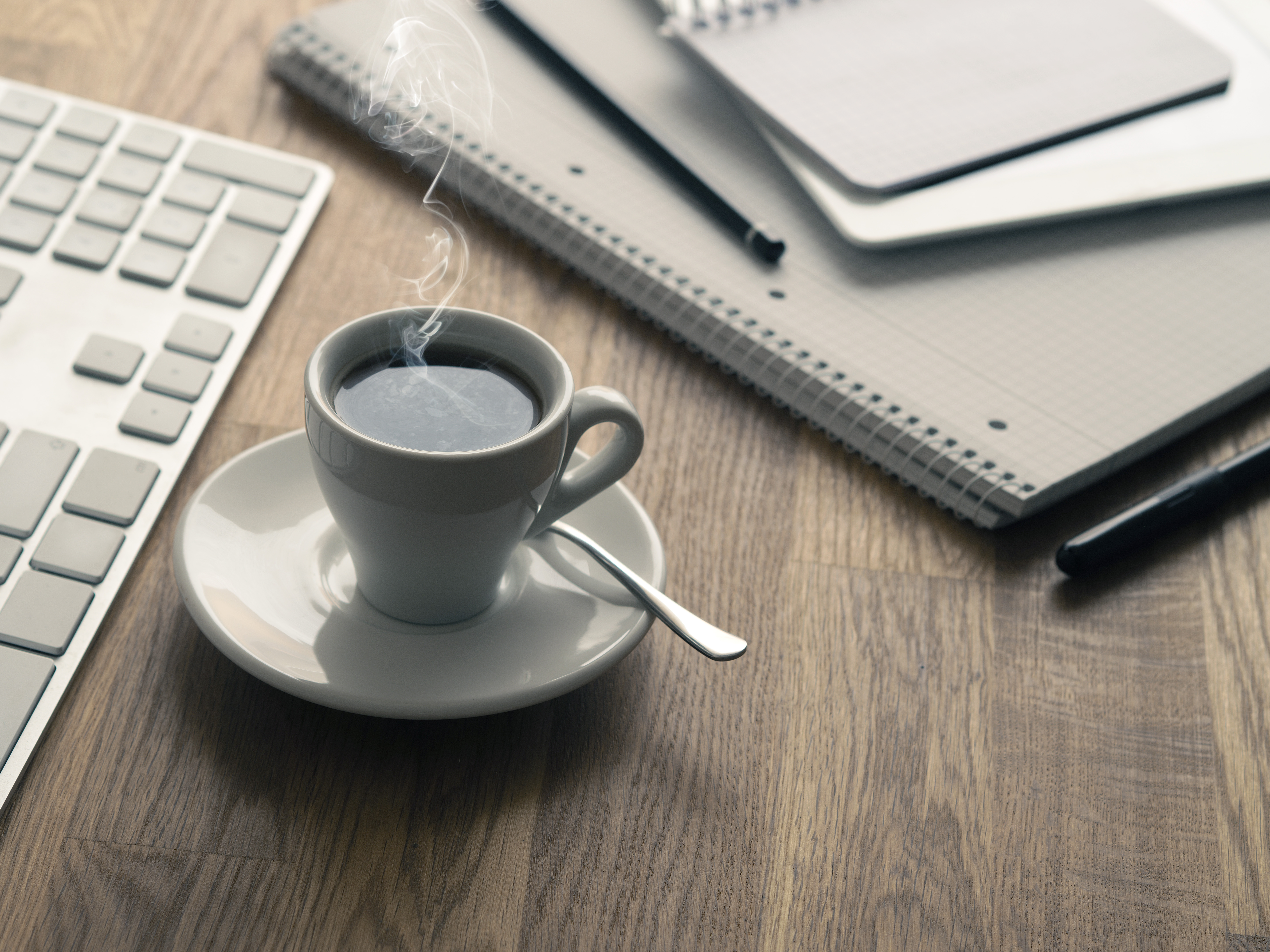 Espresso zrobione z kapsułek Saquella Decaf Espresso Aromatico stojące na biurku obok klawiatury i notatników biurowych.