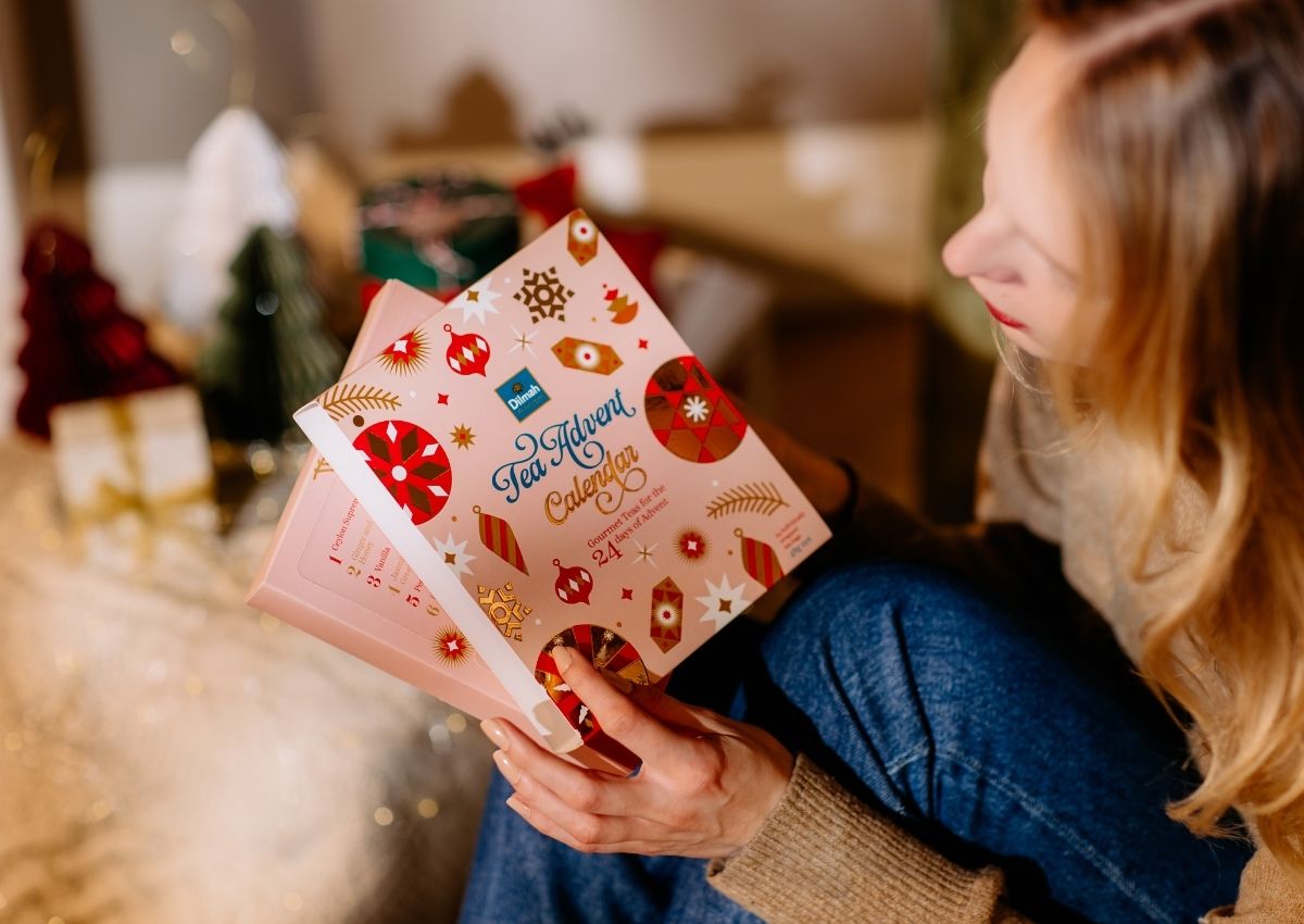 Kobieta rozpakowuje prezent, jakim jest kalendarz adwentowy z herbatą Dilmah Advent Calendar.