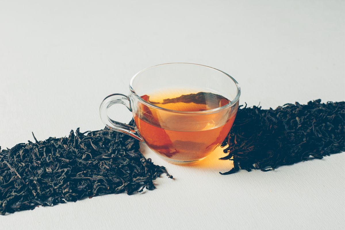 Filiżanka z herbatą Dilmah Darjeeling. Wokół rozsypany susz herbaciany.