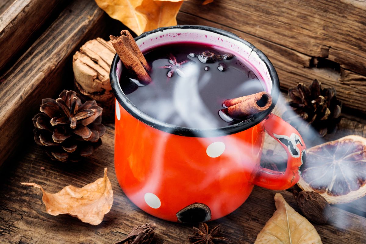 Parujący napar Dilmah Naturally Spicy Berry w metalowym kubeczku i jesiennej scenerii.