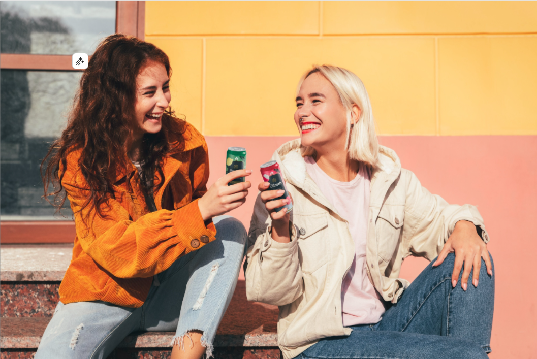 Dwie kobiety rozmawiające w swobodnej, letniej atmosferze, delektujące się herbatą Dilmah Jasmine Flavor Green Ice Tea oraz Dilmah Lychee Black Ice Tea.