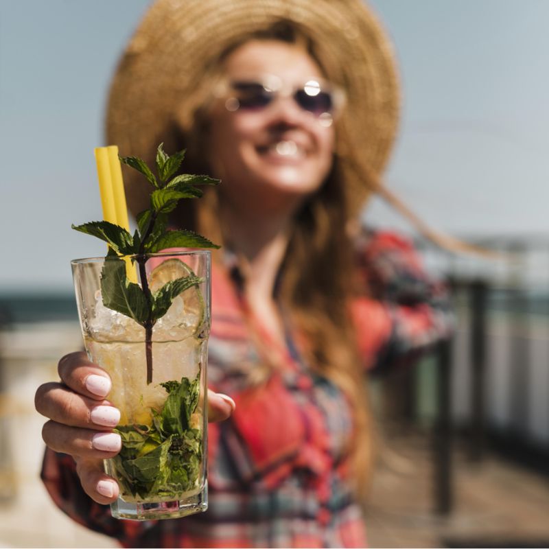 Kobieta w letnim stroju prezentująca swoje domowe Virgin Mojito.